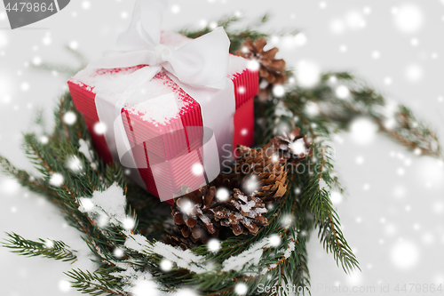 Image of christmas gift and fir wreath with cones on snow