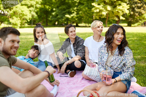 Image of happy friends with drinks at picnic in summer park