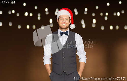 Image of happy man in santa hat and suit at christmas