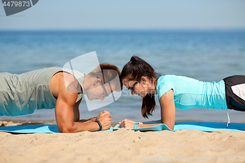 Image of couple doing plank exercise on summer beach