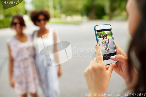 Image of woman photographing her friends in summer
