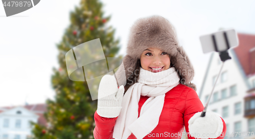 Image of woman taking selfie over christmas tree