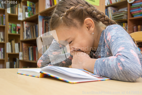 Image of Girl laughing while reading a book in the library