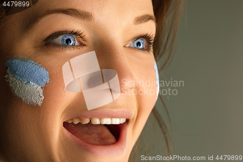 Image of Portrait of a woman with the flag of the Argentina painted on her face.