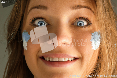 Image of Portrait of a woman with the flag of the Argentina painted on her face.