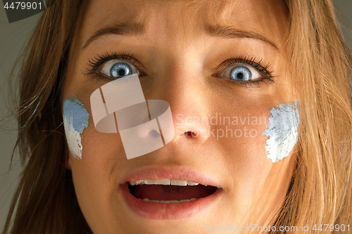 Image of Portrait of a woman with the flag of the Argentina painted on her face.