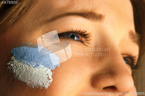 Image of Portrait of a woman with the flag of the Argentina painted on her face.