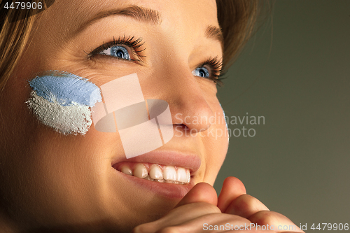 Image of Portrait of a woman with the flag of the Argentina painted on her face.