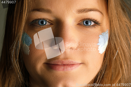 Image of Portrait of a woman with the flag of the Argentina painted on her face.