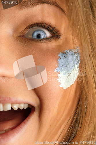 Image of Portrait of a woman with the flag of the Argentina painted on her face.