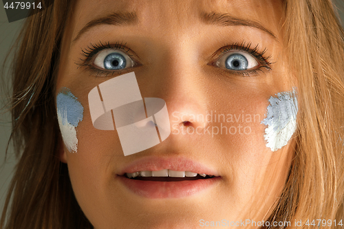 Image of Portrait of a woman with the flag of the Argentina painted on her face.