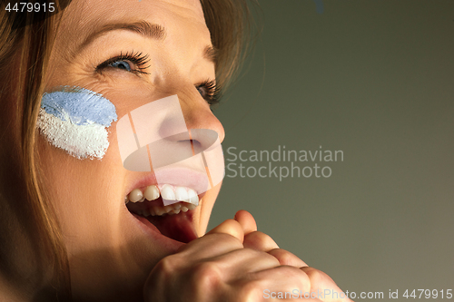 Image of Portrait of a woman with the flag of the Argentina painted on her face.