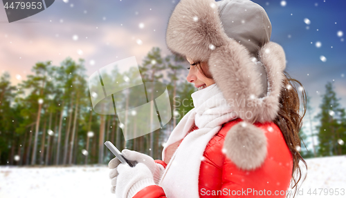 Image of happy woman with smartphone in winter