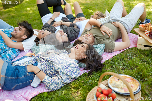 Image of happy friends chilling on picnic blanket at summer