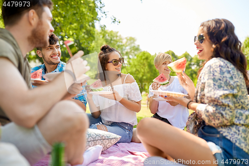 Image of happy friends eating watermelon at summer picnic