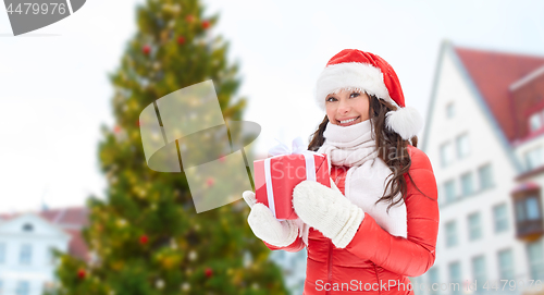 Image of happy woman with gift over christmas tree