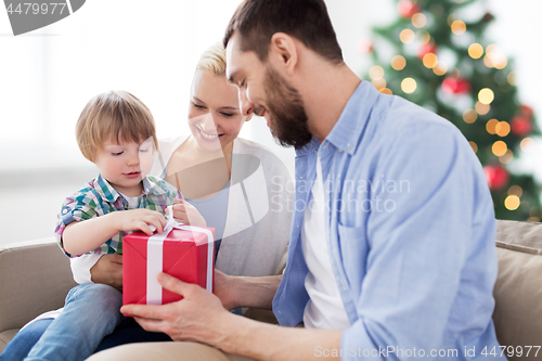 Image of happy family with christmas gift at home