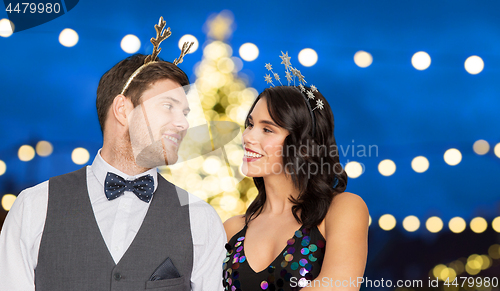 Image of couple with party props over christmas tree lights