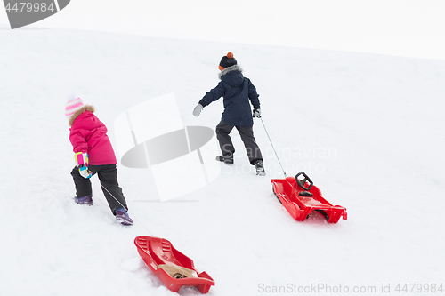 Image of kids with sleds climbing snow hill in winter