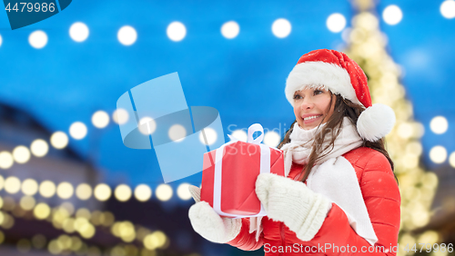 Image of happy woman with gift over christmas tree