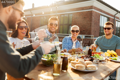 Image of friends having dinner or bbq party on rooftop