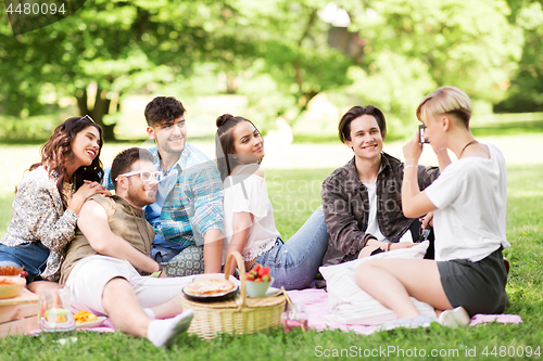 Image of friends photographing at picnic in summer park