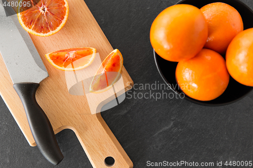 Image of close up of oranges and knife on cutting board