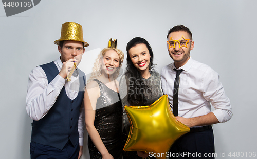 Image of happy friends with golden party props posing