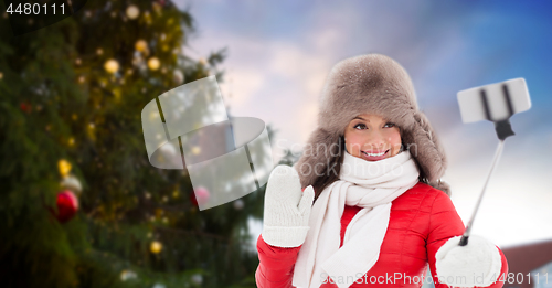 Image of woman taking selfie over christmas tree