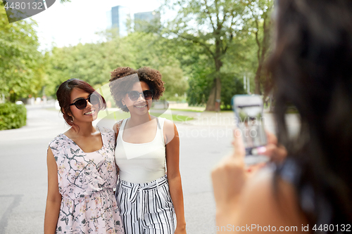 Image of woman photographing her friends in summer park