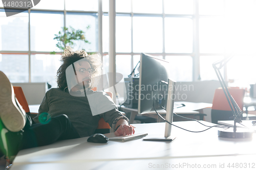 Image of businessman sitting with legs on desk