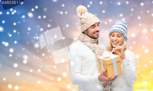 Image of smiling couple in winter clothes with gift box