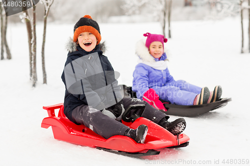 Image of happy little kids sliding on sleds in winter