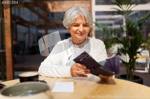 Image of senior woman with wallet paying bill at cafe