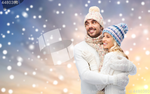 Image of happy couple in winter clothes hugging over snow