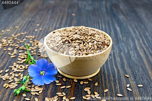 Image of Flaxen brown seed in bowl with blue flower on board