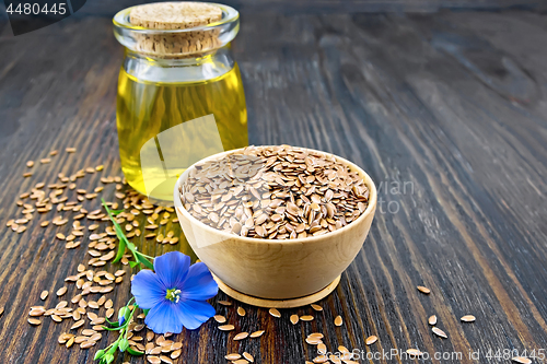 Image of Flaxen brown seed in bowl with oil on dark board