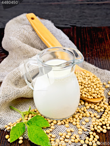 Image of Milk soy in jug with spoon and leaf on dark board