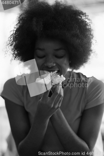 Image of woman with afro hairstyle eating tasty pizza slice