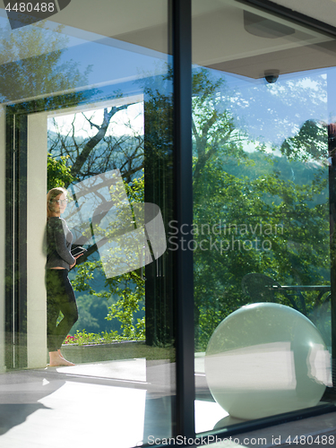 Image of women using tablet computer in front of luxury home villa