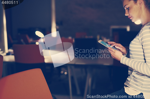 Image of woman working on digital tablet in night office