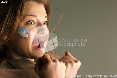 Image of Portrait of a woman with the flag of the Argentina painted on her face.