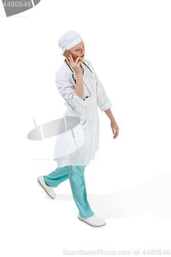 Image of Beautiful young woman in white coat going at studio. Full length studio shot isolated on white.