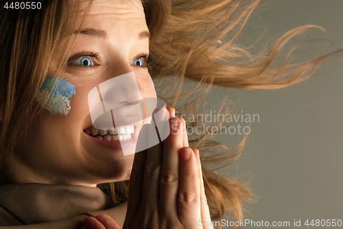 Image of Portrait of a woman with the flag of the Argentina painted on her face.