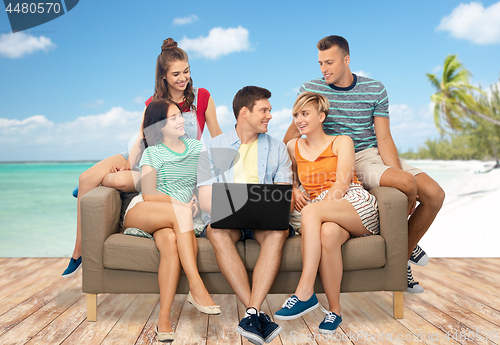 Image of friends with laptop sitting on sofa over beach