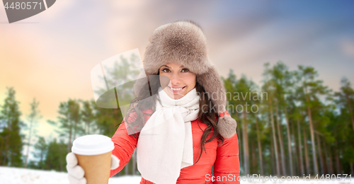 Image of woman in fur hat with coffee over winter forest