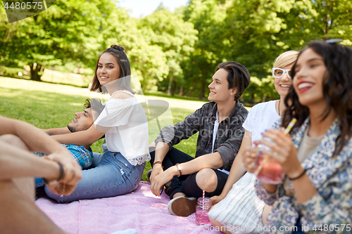 Image of happy friends with drinks at picnic in summer park