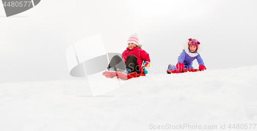 Image of girls sliding on sleds down snow hill in winter