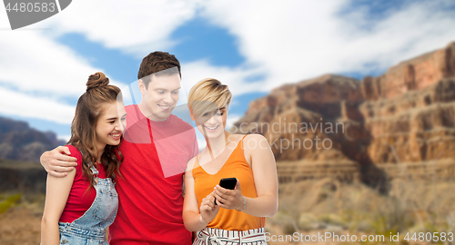 Image of friends with smartphone over grand canyon