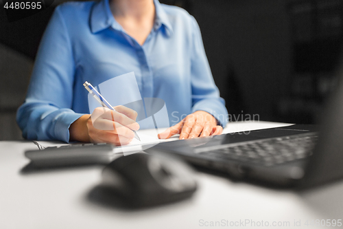 Image of businesswoman with papers working at night office